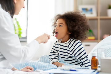 Image showing doctor checking sick girl's throat at home