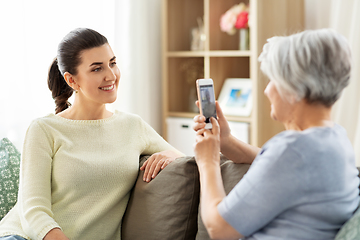 Image showing senior mother photographing adult daughter at home