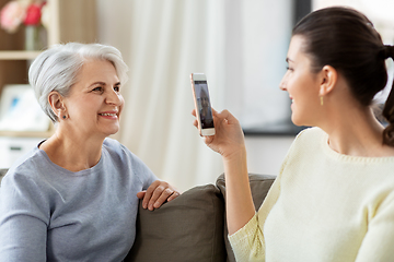 Image showing adult daughter photographing senior mother at home