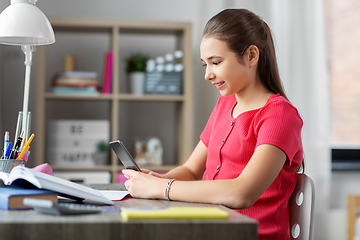 Image showing girl with smartphone distracting from homework