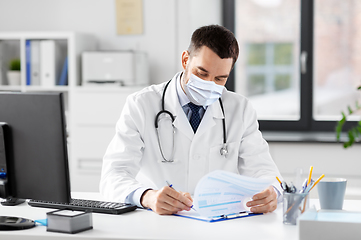 Image showing smiling male doctor with clipboard at hospital