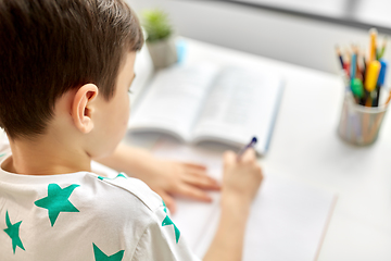 Image showing close up of boy writing to notebook at home