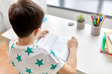 Image showing boy with earphones and textbook learning at home