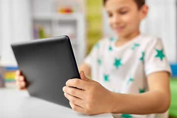 Image showing close up of boy with tablet pc sitting at table