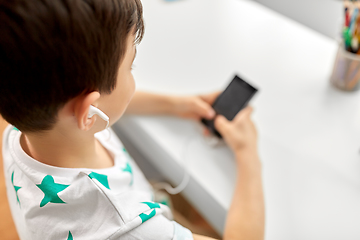 Image showing boy with earphones and smartphone at home