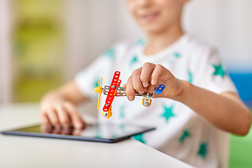 Image showing happy little boy playing with airplane toy at home