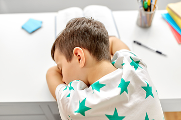 Image showing close up of tired boy sleeping on table at home