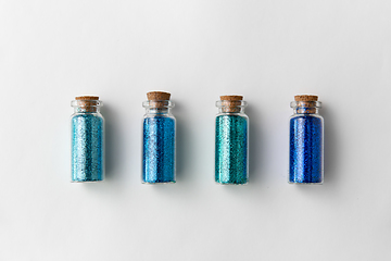 Image showing blue glitters in bottles over white background