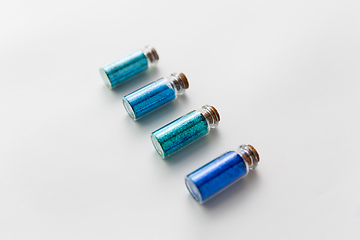 Image showing blue glitters in bottles over white background