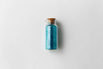 Image showing blue glitters in bottle over white background