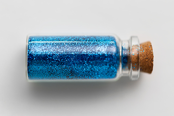 Image showing blue glitters in bottle over white background