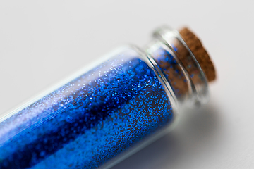 Image showing blue glitters in bottle over white background