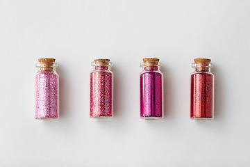 Image showing red glitters in bottles over white background