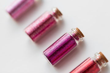 Image showing red glitters in bottles over white background