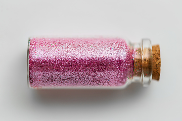 Image showing pink glitters in bottle over white background