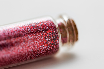 Image showing red glitters in bottle over white background