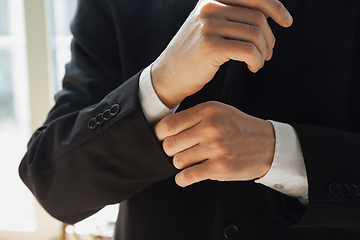 Image showing Close up of caucasian male hands, wearing classic black jacket