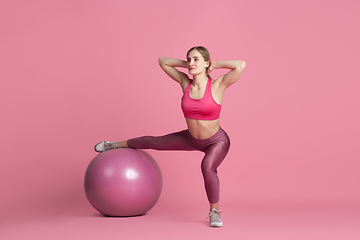 Image showing Beautiful young female athlete practicing on pink studio background, monochrome portrait