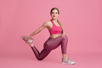 Image showing Beautiful young female athlete practicing on pink studio background, monochrome portrait