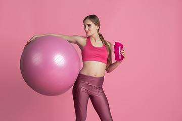 Image showing Beautiful young female athlete practicing on pink studio background, monochrome portrait