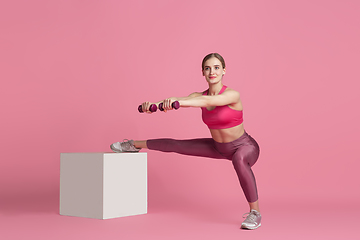 Image showing Beautiful young female athlete practicing on pink studio background, monochrome portrait