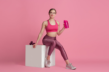 Image showing Beautiful young female athlete practicing on pink studio background, monochrome portrait