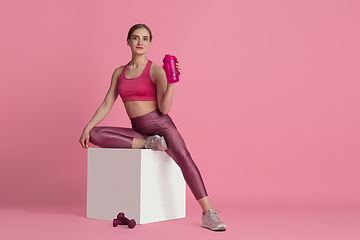 Image showing Beautiful young female athlete practicing on pink studio background, monochrome portrait