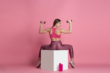 Image showing Beautiful young female athlete practicing on pink studio background, monochrome portrait