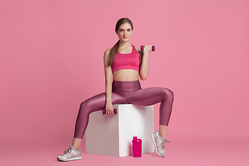 Image showing Beautiful young female athlete practicing on pink studio background, monochrome portrait