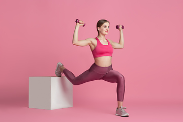 Image showing Beautiful young female athlete practicing on pink studio background, monochrome portrait