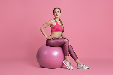 Image showing Beautiful young female athlete practicing on pink studio background, monochrome portrait