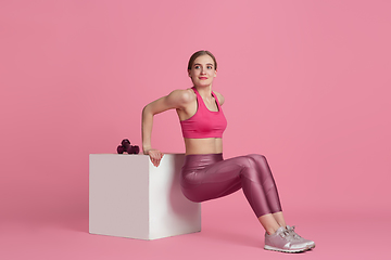 Image showing Beautiful young female athlete practicing on pink studio background, monochrome portrait