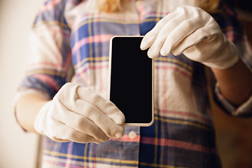 Image showing Coronavirus. Novel coronavirus 2019-nCoV , COVID-29, hands of a woman in gloves holdes smartphone