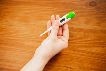 Image showing Coronavirus. Novel coronavirus 2019-nCoV , COVID-29, hands of a woman holding thermometer