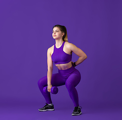 Image showing Beautiful young female athlete practicing on purple studio background, monochrome portrait