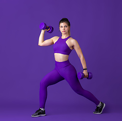 Image showing Beautiful young female athlete practicing on purple studio background, monochrome portrait