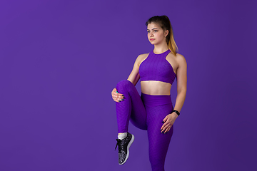 Image showing Beautiful young female athlete practicing on purple studio background, monochrome portrait