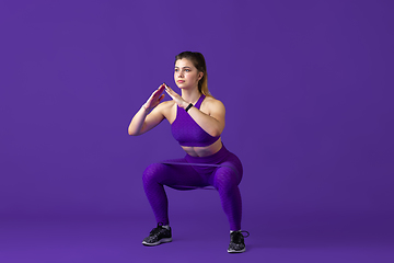 Image showing Beautiful young female athlete practicing on purple studio background, monochrome portrait