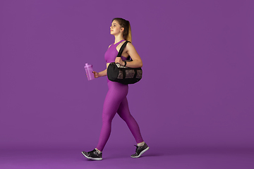 Image showing Beautiful young female athlete practicing on purple studio background, monochrome portrait