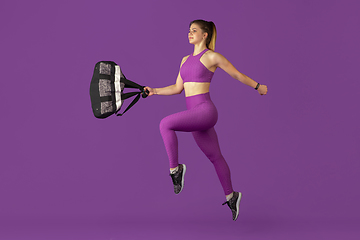 Image showing Beautiful young female athlete practicing on purple studio background, monochrome portrait