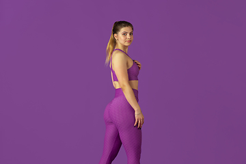 Image showing Beautiful young female athlete practicing on purple studio background, monochrome portrait