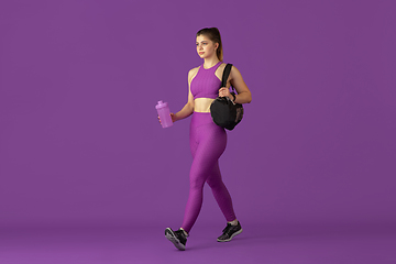 Image showing Beautiful young female athlete practicing on purple studio background, monochrome portrait