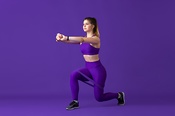 Image showing Beautiful young female athlete practicing on purple studio background, monochrome portrait