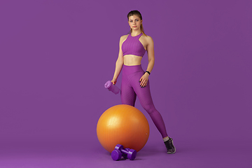 Image showing Beautiful young female athlete practicing on purple studio background, monochrome portrait