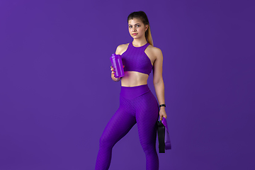 Image showing Beautiful young female athlete practicing on purple studio background, monochrome portrait