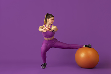 Image showing Beautiful young female athlete practicing on purple studio background, monochrome portrait