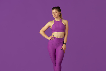 Image showing Beautiful young female athlete practicing on purple studio background, monochrome portrait