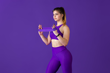 Image showing Beautiful young female athlete practicing on purple studio background, monochrome portrait