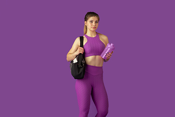 Image showing Beautiful young female athlete practicing on purple studio background, monochrome portrait