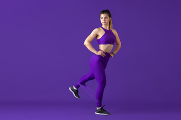 Image showing Beautiful young female athlete practicing on purple studio background, monochrome portrait